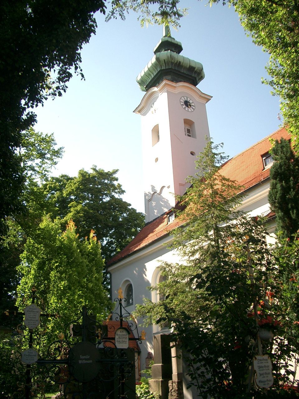 Turm der Kirche St. Georg zwischen Grabstätten auf dem Friedhof Bogenhausen